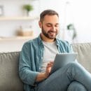 joyful-millennial-man-sitting-on-sofa-with-tablet-2021-09-03-16-19-08-utc.jpg